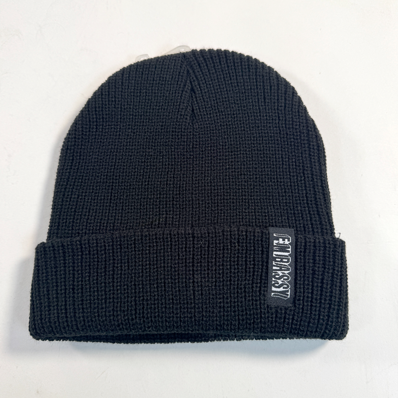 Black beanie with a brand label on a light gray background