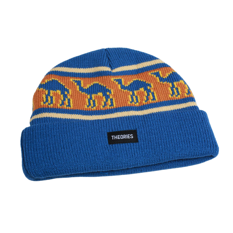 Blue knit beanie with camel pattern and 'Theories' label on a light gray background